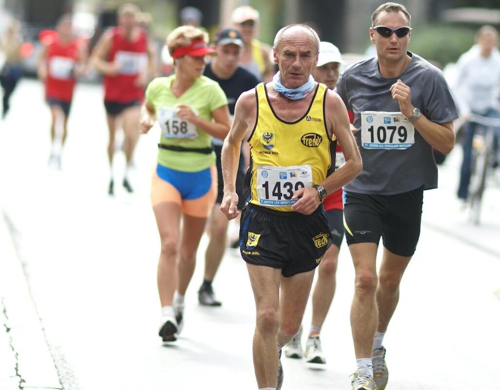 A diverse group of athletes participates in an outdoor marathon race, demonstrating energy and fitness.