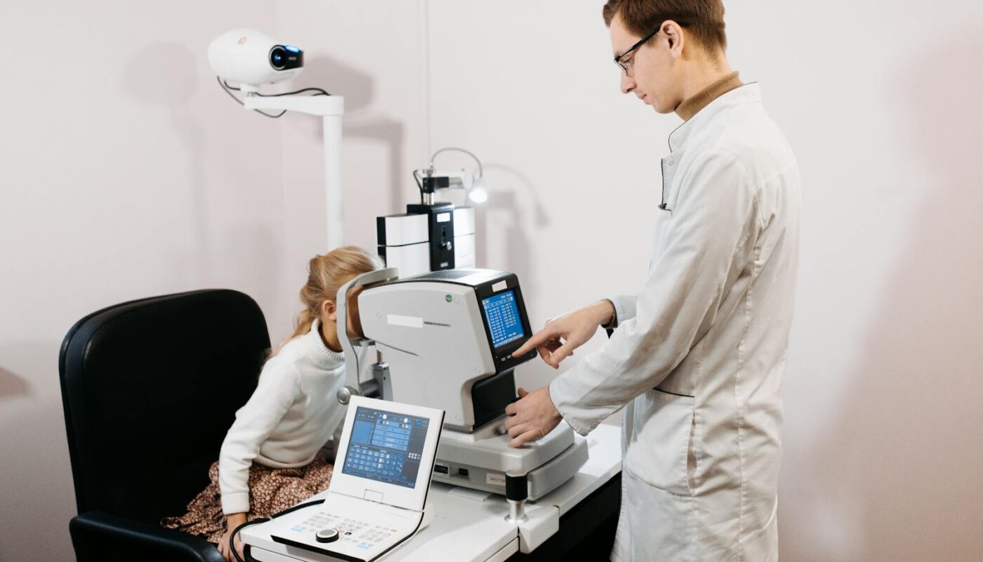 A professional optometrist examines a child's eyes using advanced equipment.