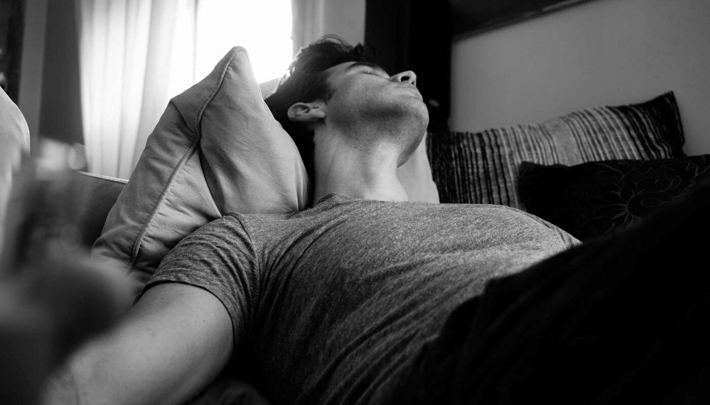 grayscale photo of man laying on bed