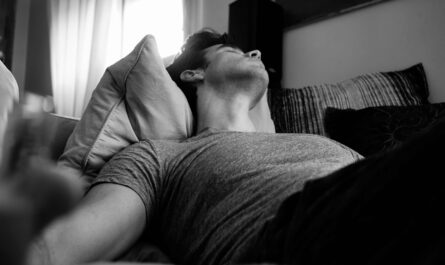 grayscale photo of man laying on bed